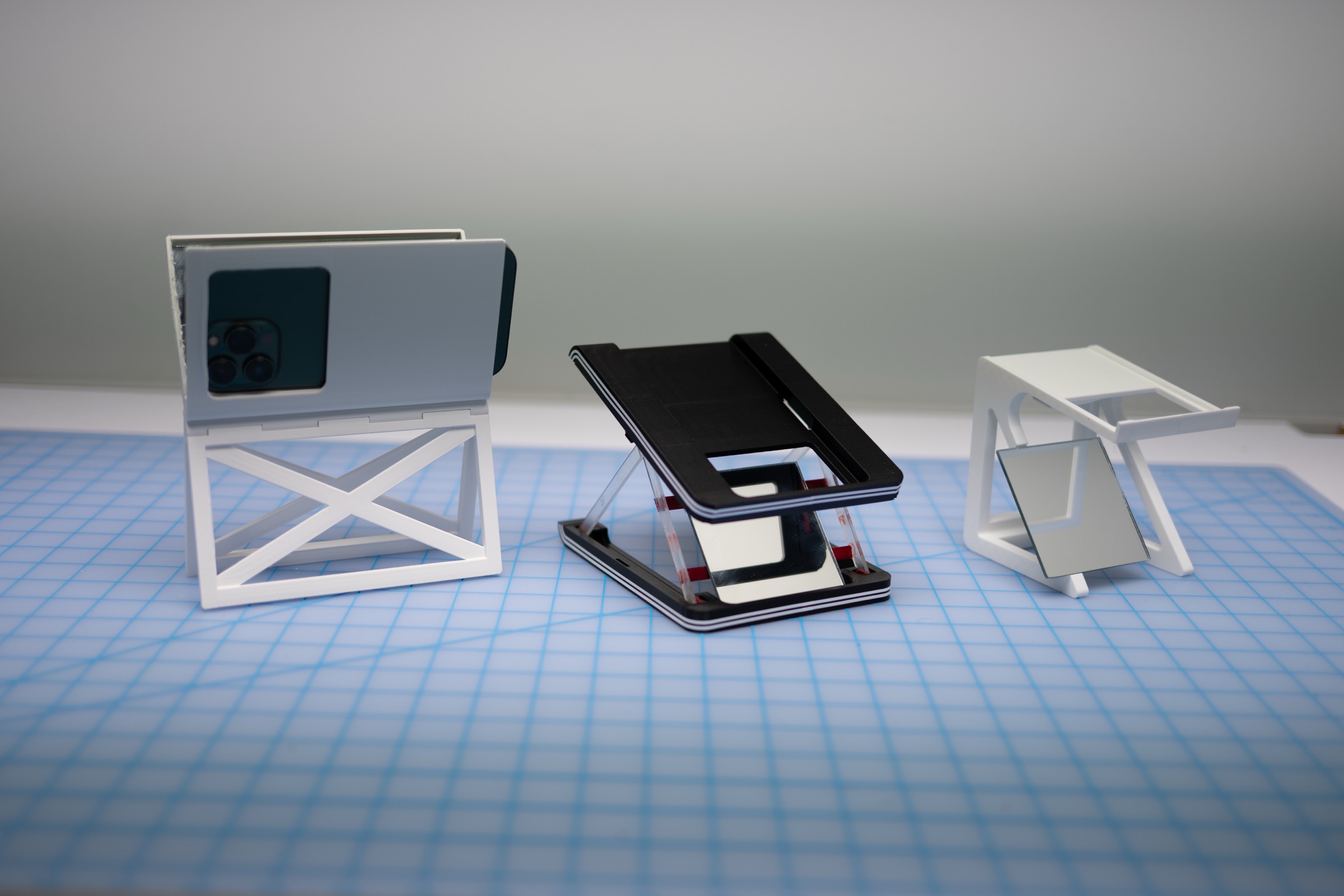 Three Dialed phone stand prototypes lined up from newest to oldest